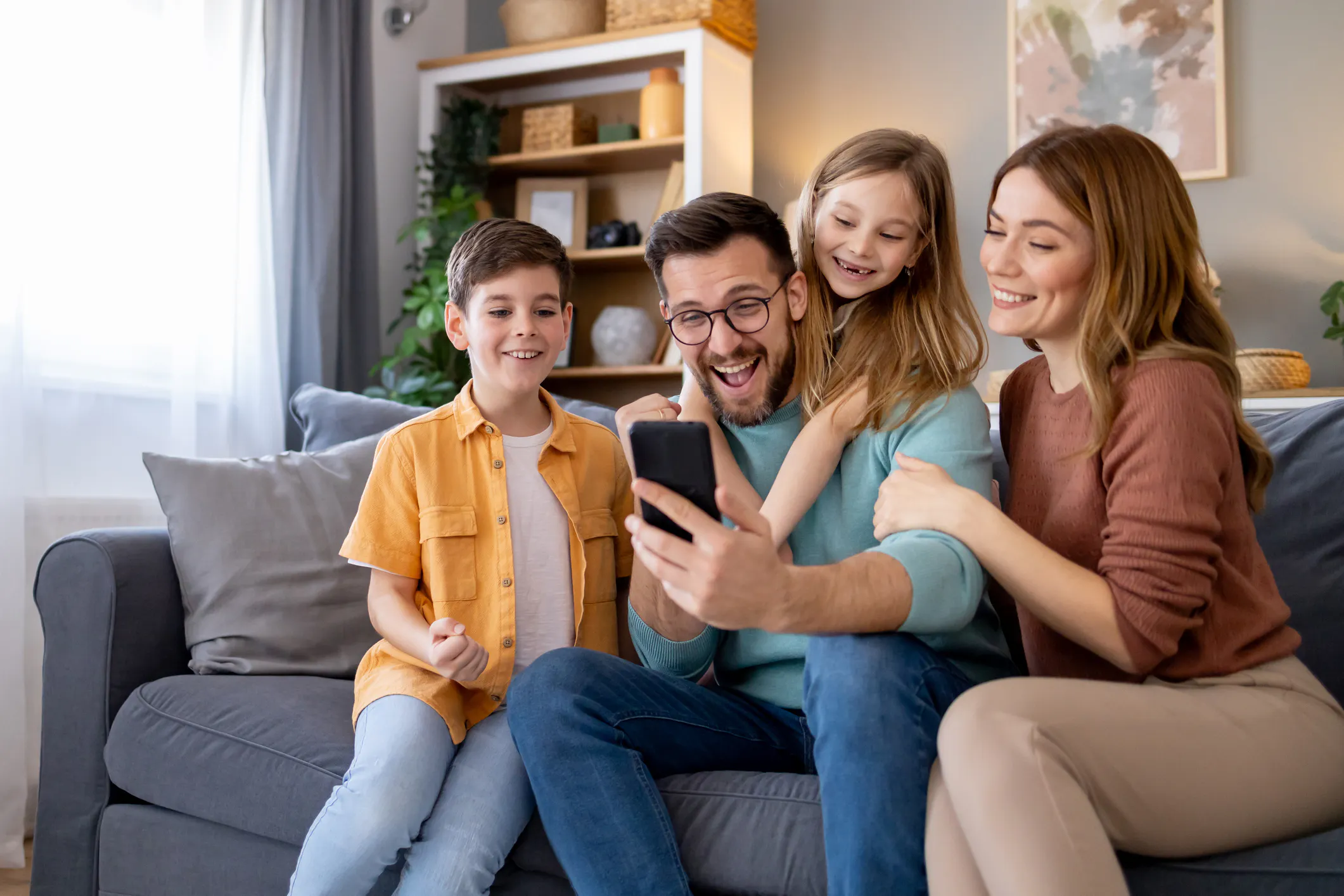 A family looking at a phone together on their sofa
